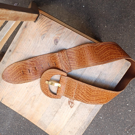Handmade Vintage 70s retro fashion leather belt with an oversized silhouette photographed on a rustic brown wooden chair. The image showcases the leather belt&#39;s unique grain pattern