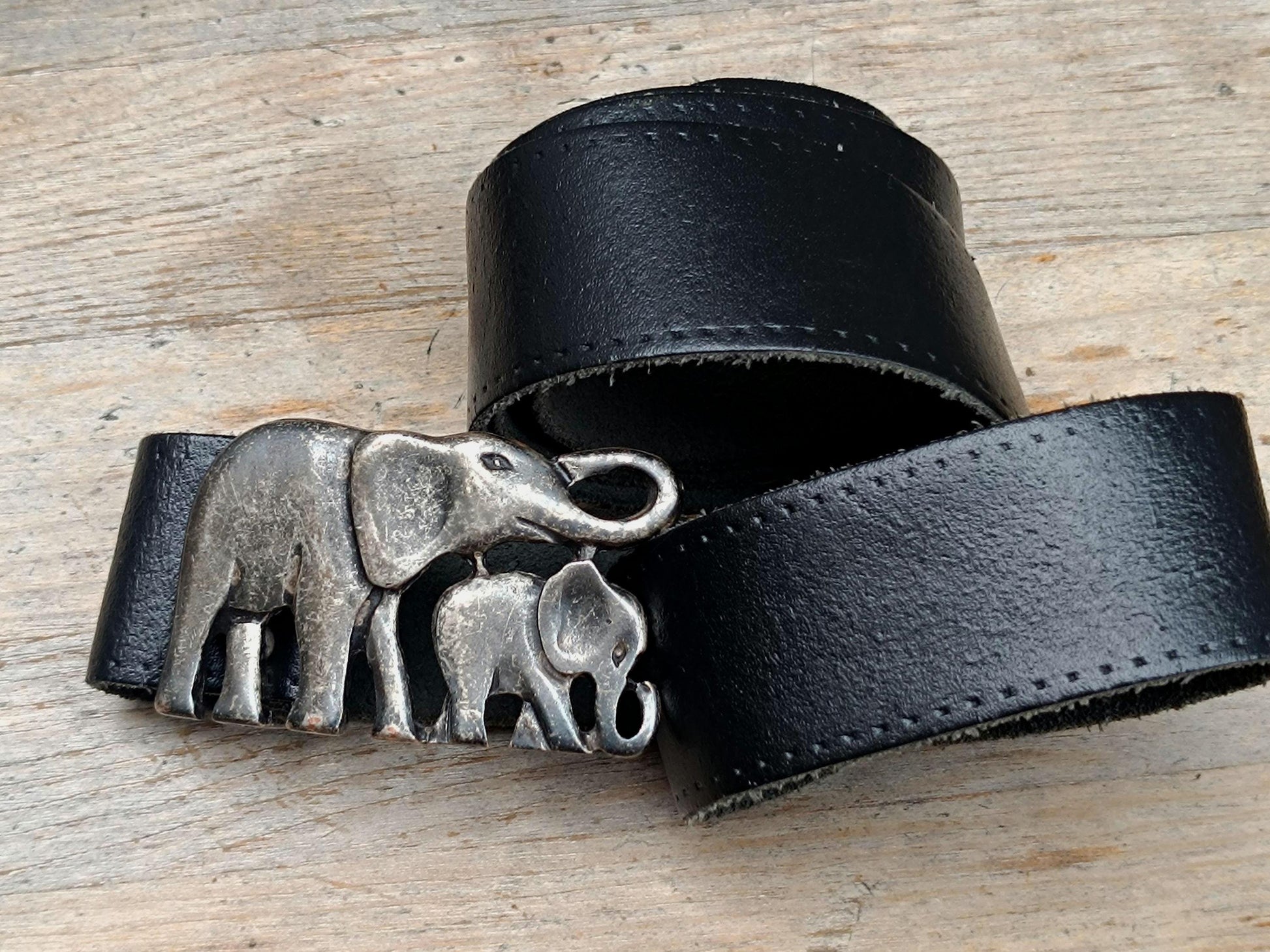 Vintage elephant Buckle black Leather Belt photographed on a brown rustic wooden surface. The Handmade Boho Chic Accessory is perfect for festival style