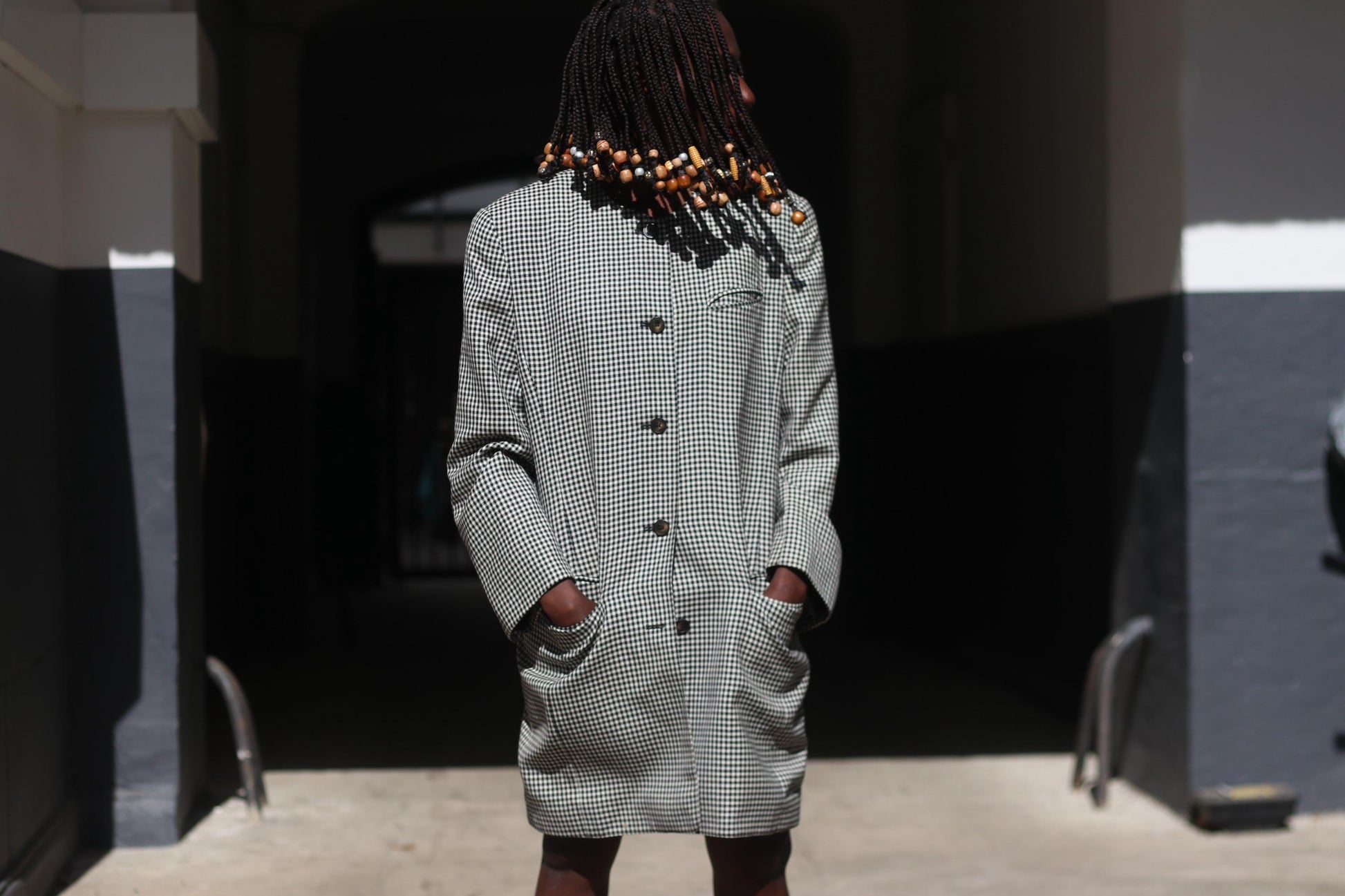 Close-up of the black and white gingham fabric and large statement buttons on a female model emphasizing the texture and vintage craftsmanship