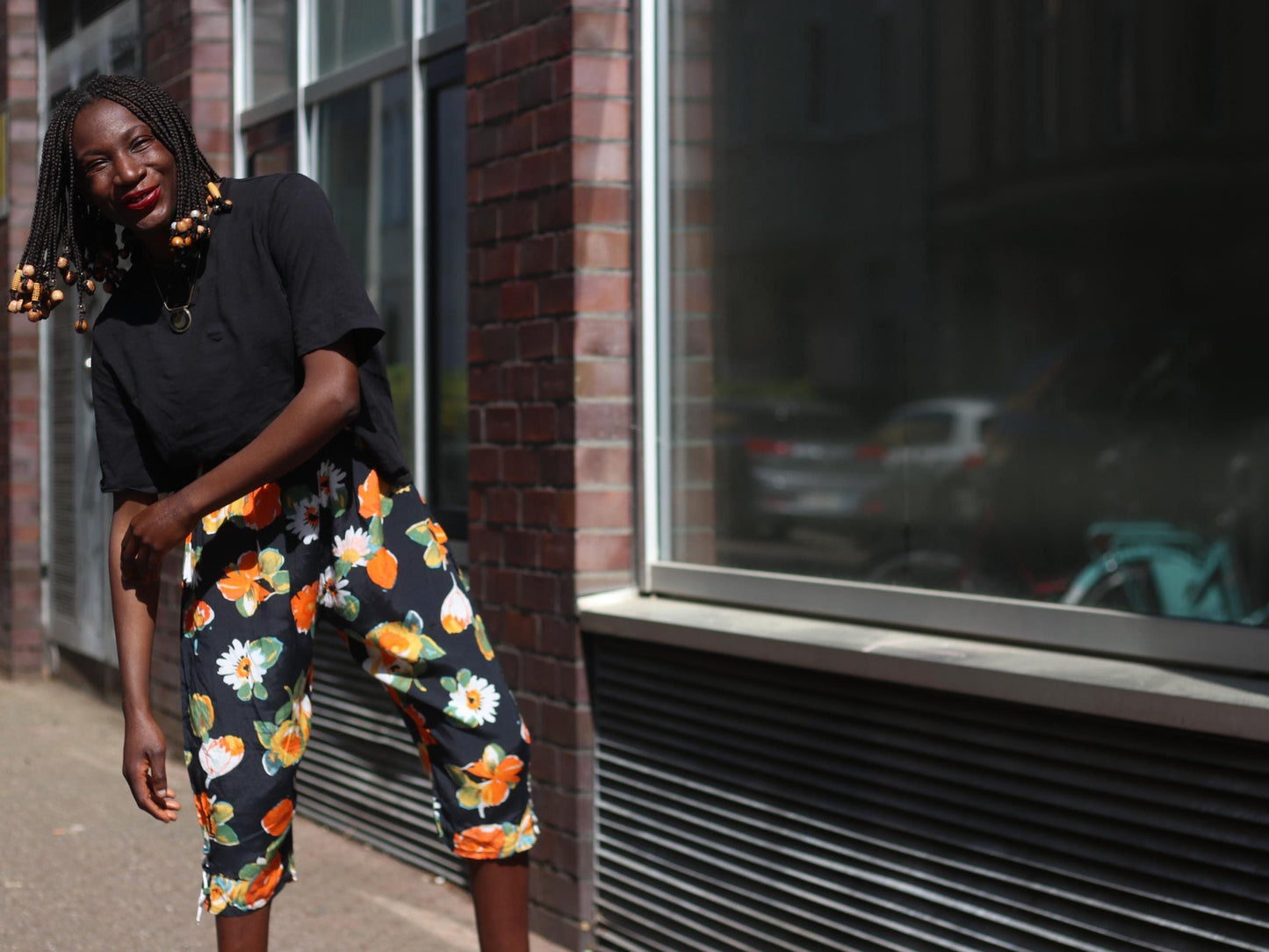 Fashion-forward street style image featuring vintage capris with vibrant flower patterns, captured against an industrial city backdrop.