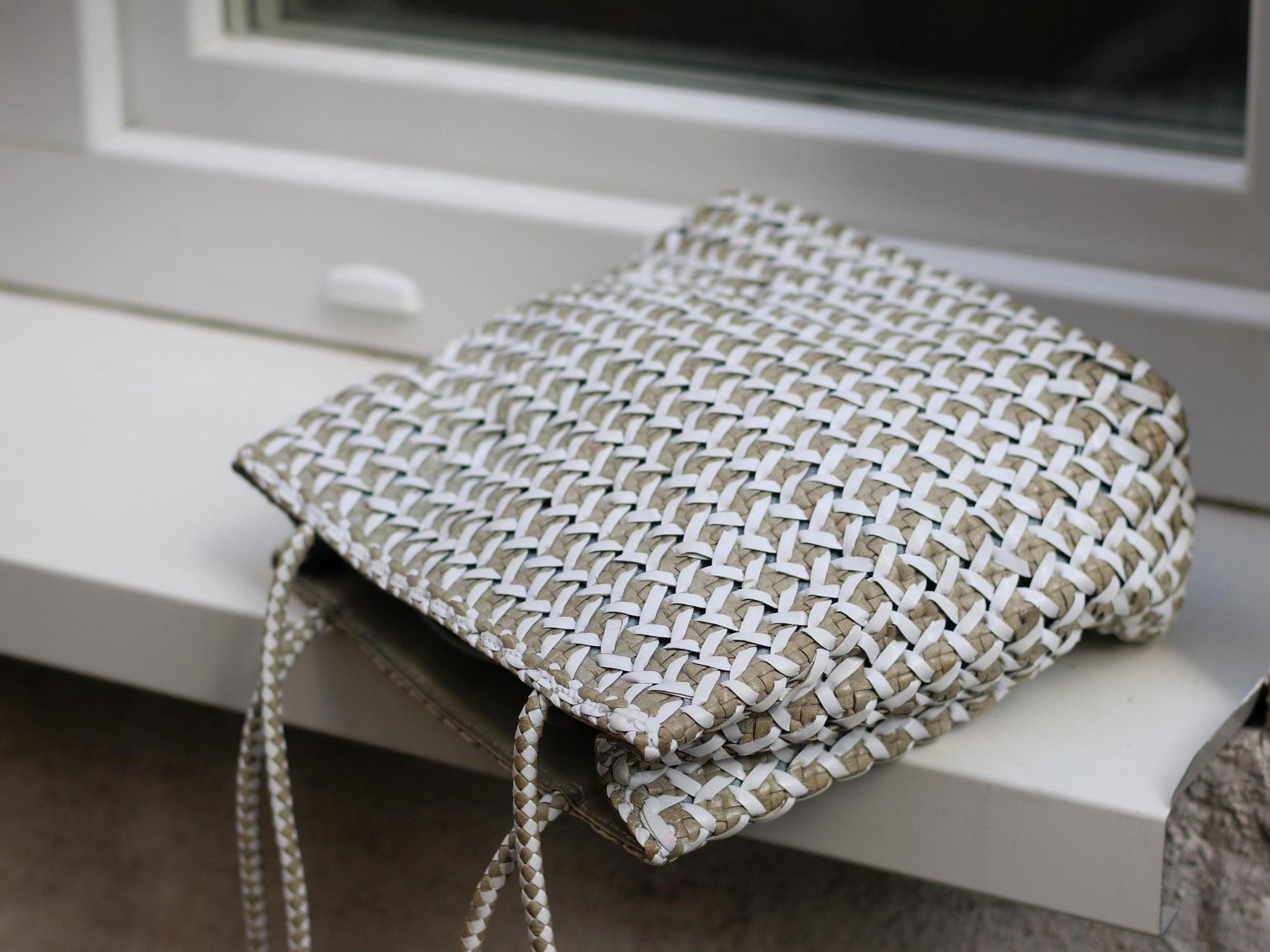 Vintage white and brown minimalist leather woven bag by Italian brand Romani Fratelli photographed on a white window sill laying flat