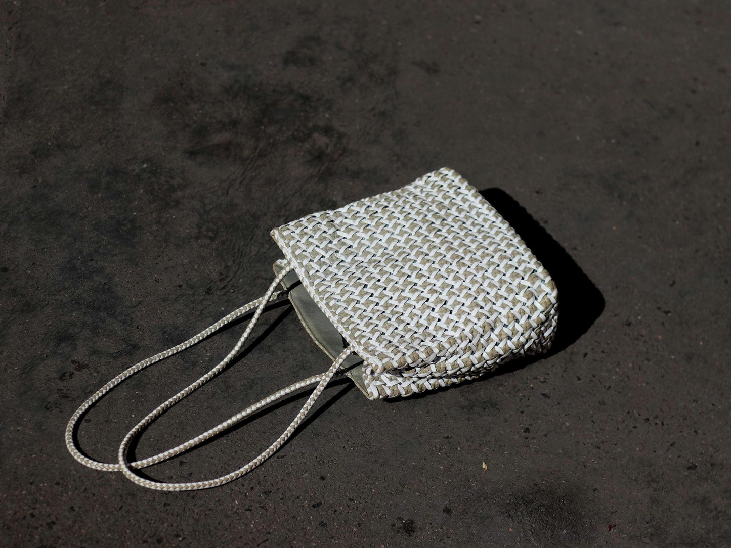 Vintage White leather woven bag by Italian brand Romani Fratelli photographed on a grey surface to accentuate the minimalist nature of the  Leather Purse.