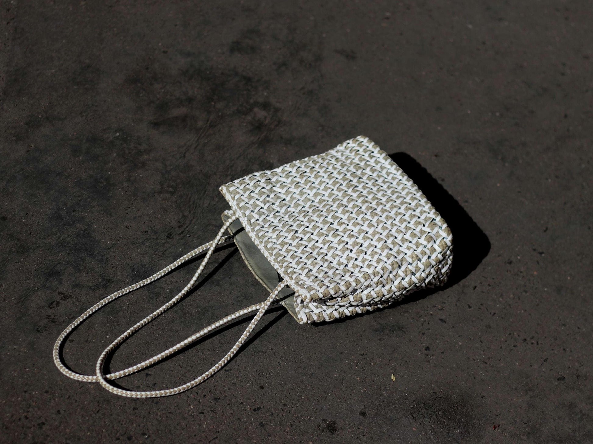 Vintage White leather woven bag by Italian brand Romani Fratelli photographed on a grey surface to accentuate the minimalist nature of the  Leather Purse.