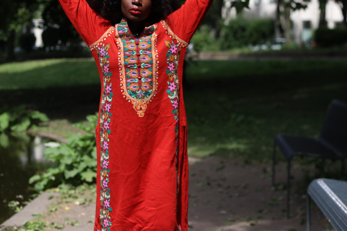 Close-up of a Folk-inspired summer dress with vibrant embroidery and flowing silhouette on a female model photographed outdoors.