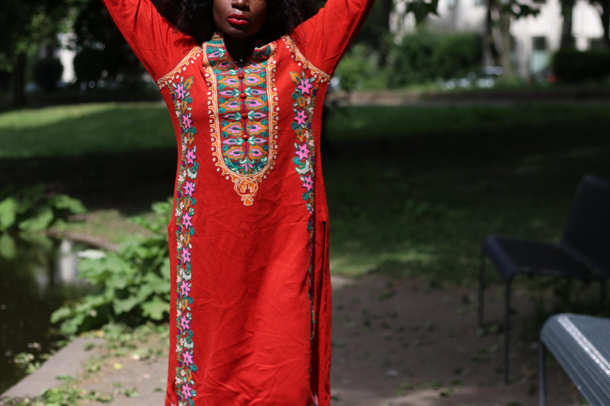 Close-up of a Folk-inspired summer dress with vibrant embroidery and flowing silhouette on a female model photographed outdoors.