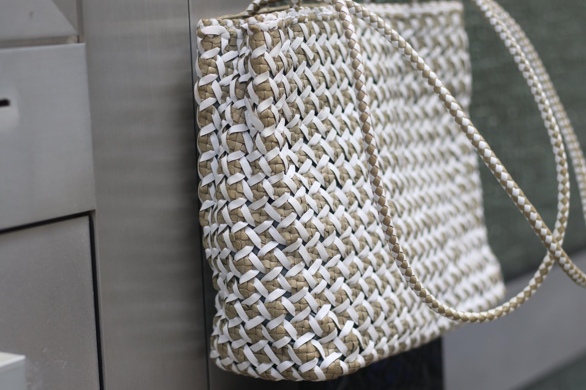 Retro 80s White leather woven bag is photographed resting against a grey surface to accentuate the minimalist nature of the  Leather Purse.
