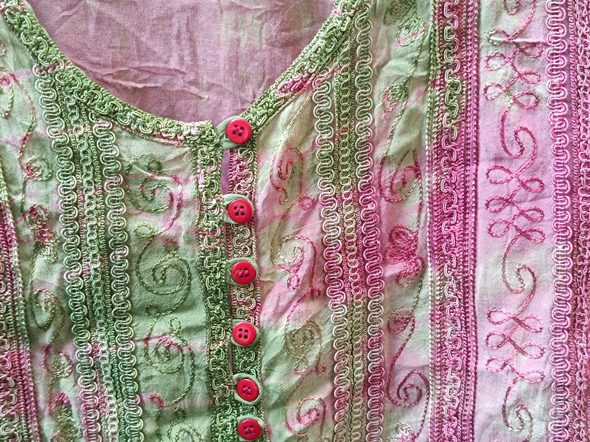 Close-up detail of the vintage 90s boho chic top with pink and green patterned fabric with unique stitching and red button accents