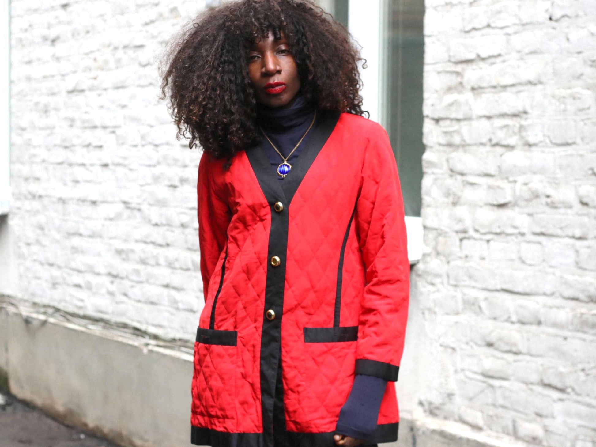 Model wearing a vintage red and black quilted blazer coat, showcasing its fit and collarless V-neck design.