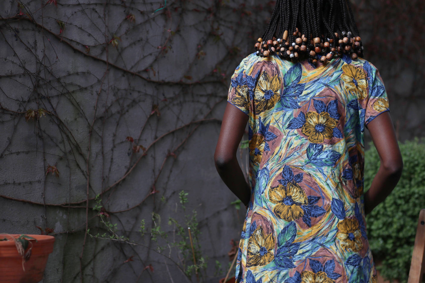 A-line vintage dress in bold blue, green, and ochre hues, styled effortlessly against a moody garden backdrop.